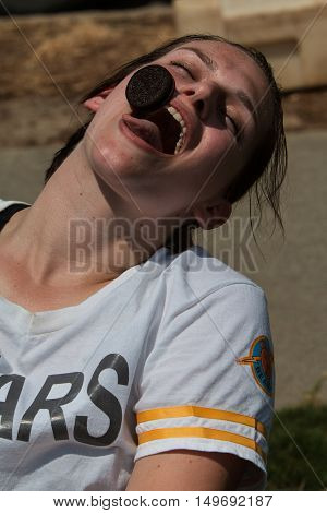 ATLANTA, GA - JULY 2016: A young woman tries to carefully move an Oreo cookie from her forehead into her mouth in a game called 