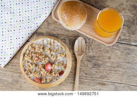 Bowl of breakfast muesli with oat and wheat flakes mixed with dried fruit and nuts in a wooden bowl for a healthy nutritious meal.Served with wholewheat bread and fresh orange juice.