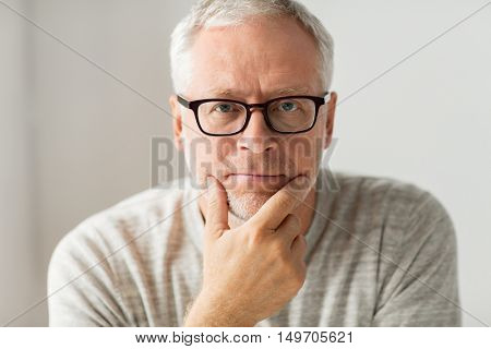 old age, problem and people concept - close up of senior man in glasses thinking
