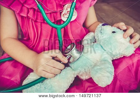 Child Playing Doctor Or Nurse With Plush Toy Bear At Home. Vintage Tone Effect.