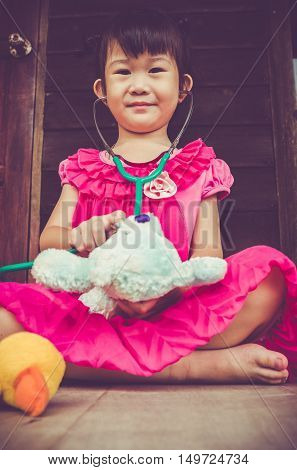 Closeup Adorable Asian Girl Playing Doctor Or Nurse With Plush Toy Bear At Home. Vintage Tone Effect