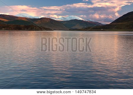 Snowcapped mountains by the sea at sunset at Ullapool Scotland