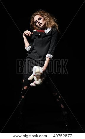 Horror shot: a scary monster girl with rabbit toy and bloody cleaver in hands