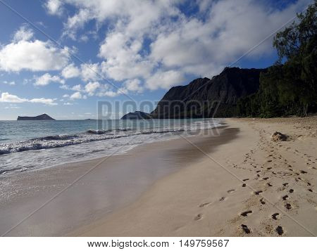foot prints in the sand with Gentle wave lap on Waimanalo Beach looking towards Rabbit island and Rock island on a nice day Oahu Hawaii. July 2016.