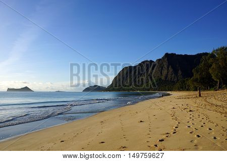 Gentle wave lap on Waimanalo Beach with foot prints in the sand looking towards Rabbit island and Rock island on a nice day Oahu Hawaii. June 2016.