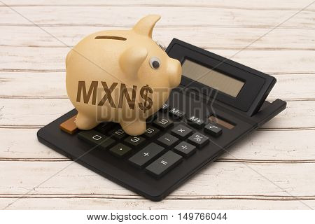 The MXN dollar currency A golden piggy bank and calculator on a wood background with symbol of dollar sign and text MXN
