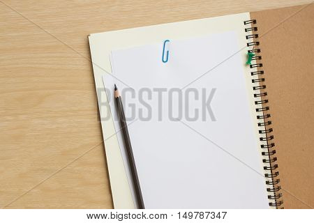 blank paper on desk / Open blank white paper notebook with copy space and a pencil lying on a wood desk, view from above / for your text or message / top view