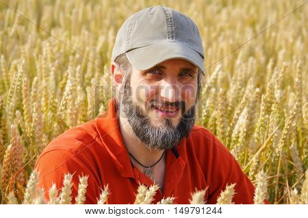 a bearded man in a cup sitting in a wheat field