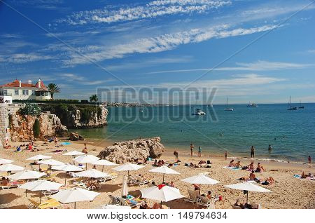 Cascais, Portugal - October 23, 2014. Praia da Rainha beach in Cascais, with people, boats and buildings in the distance.