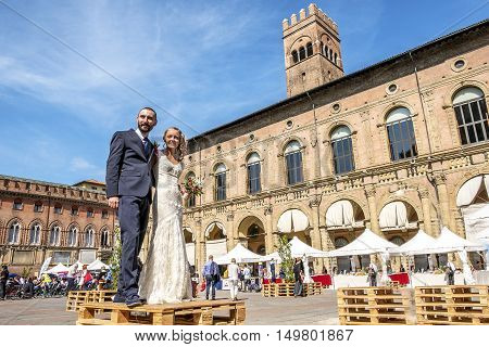 Bologna Italy 23 September 2016: two spouses getting married in italy in the Bologna main square Piazza Maggiore with the Palazzo del Podestà building in the background