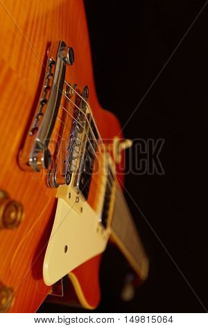 Solid body electric rock guitar closeup on the black background. Selective focus.