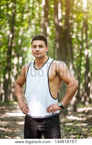 Ready to train. Muscular well built confident man resting his hands on his hips and looking at you while standing confidently in the park