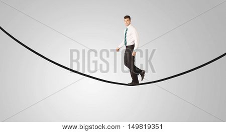 A confident smiling salesman balancing on black wire in clear grey empty space concept