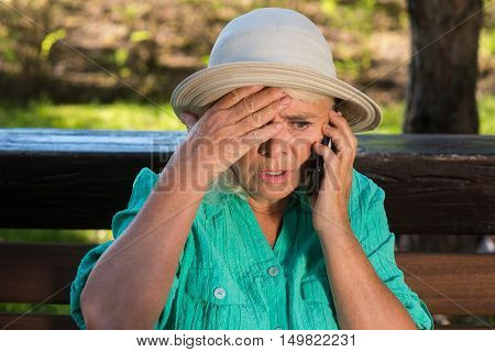 Scared woman with cell phone. Senior lady in a hat. Children are in trouble. No time to think.