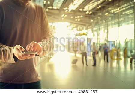 Man using smart phone at Check in Counter and Passengers in a airport departure terminal.