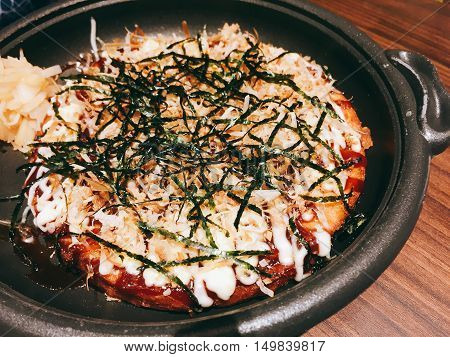 Okonomiyaki - traditional Japanese hot plate pizza with copyspace. Dark tone.