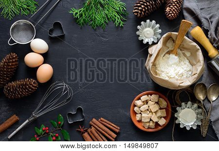 Christmas dark baking background with ingredients holiday natural decorations and utensils view from above there is a space for a text