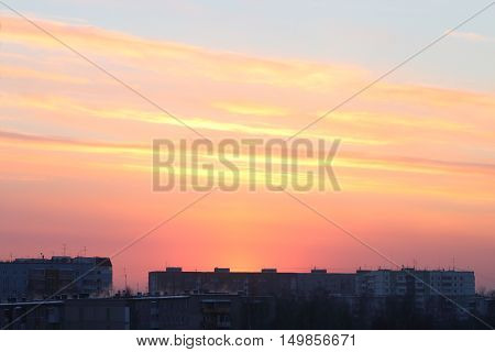 Beautiful bright sunset over roofs of residential buildings in town