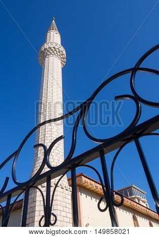 The minaret of Muslim mosques and a fragment of metal wrought fence