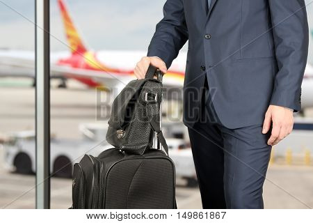 young businessman in a modern stylish suit with luggage in the airport