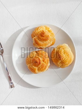 Profiteroles, choux with a custard cream, creme anglaise, whipped cream, dessert on a white plate Copy space Top view