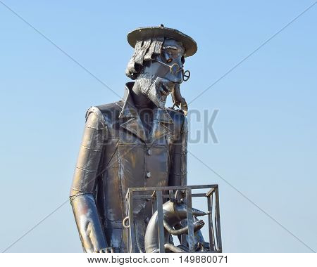 Statue Of A Furrier From Metal With A Rat In A Cage