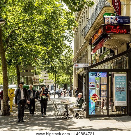 Man Sitting In A Typical Bar With Tabac Shop And Winter Gardenn At The Walk Way