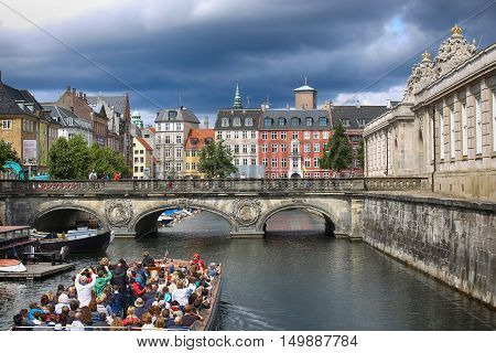 COPENHAGEN DENMARK - AUGUST 14 2016: View of canal boat with tourist and old bridge from bridge Prinsens Bro in Copenhagen Denmark on August 14 2016.