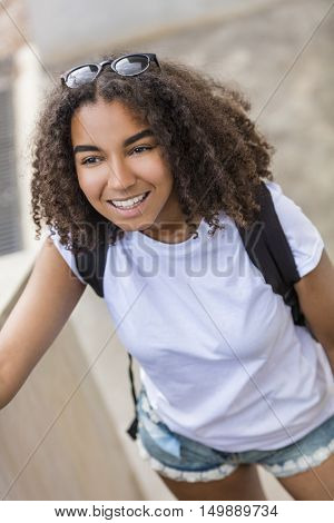 Outdoor portrait of beautiful happy mixed race African American girl teenager female young woman smiling with perfect teeth wearing shorts, t-shirt and back pack