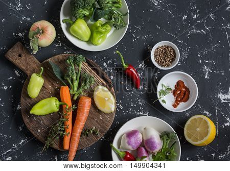 Fresh raw vegetables - carrots peppers broccoli turnips spices and herbs on dark background top view. Cooking ingredients