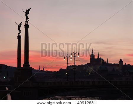 Sunset with silhouettes of Cechuv Bridge and Prague Castle in Prague Czech Republic.