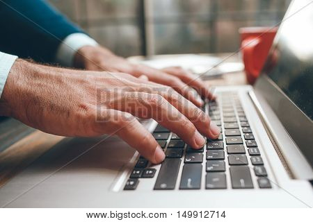 Opened laptop and male hands typing. Fingers on the keyboard. Concept of searching information, chating, communication, virtual relationship