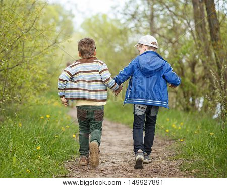 Boys friendship background. Two small funny boys running away on trail in countryside