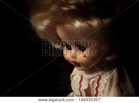 Vintage evil spooky doll with cracked surface on the face and glowing eyes