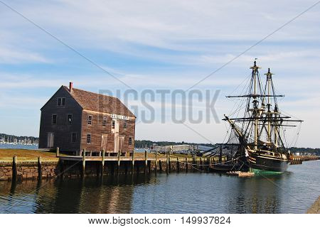 Salem, Massachusetts, United States of America - September 25, 2014. The wharves are among remnants of the shipping industry that once thrived in Salem, MA. View with historic ship, pier and timber building.