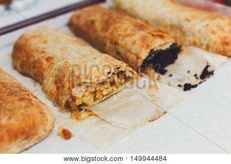Sweet strudels with poppy and apples choice on trays. Layered pastry classic austrian dessert at catering. Fattening meal. Plenty of pies outdoors. Fresh baked snack. Baking and cooking concept.