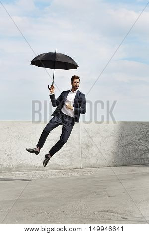 Cool Businessman jumping for joy with umbrella