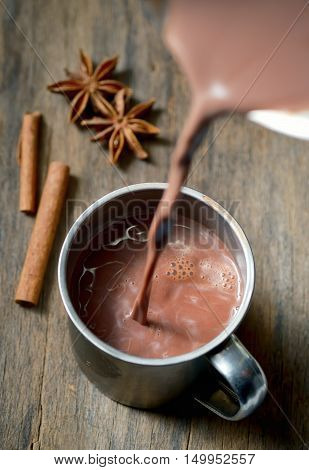 Hot chocolate with cinnamon stick on wooden table