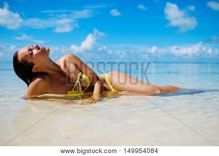 Woman in bikini sunbathing on the beach in Exuma, Bahamas.