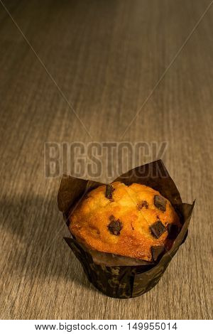 Muffin homemade with pieces of chocolate on wooden background