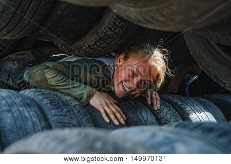 Tyumen, Russia - June 11, 2016: Race of Heroes project on the ground of the highest military and engineering school. Woman moves between old tires. Born again stage