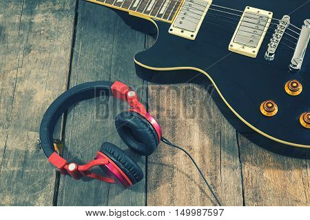Guitar recording scene. An electric guitar memo pad and a professional grade headphones on a rustic or bare wooden tablevintage effect.