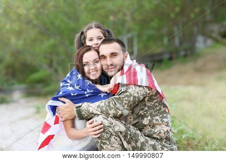 US army soldier with family and USA flag in park