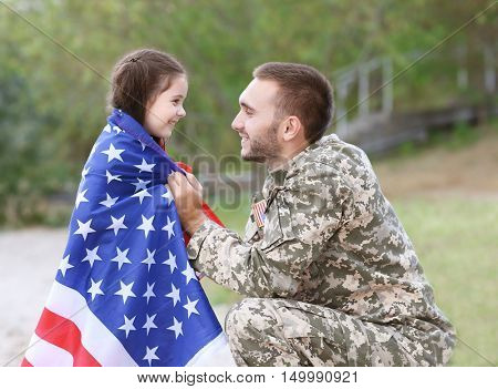 US army soldier with daughter and USA flag in park