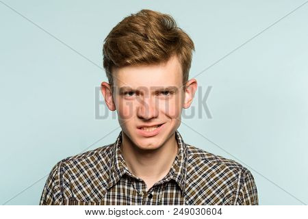 Threatening Intimidating Sneer. Crazy Looking Man With A Smirk. Portrait Of A Young Guy On Light Bac