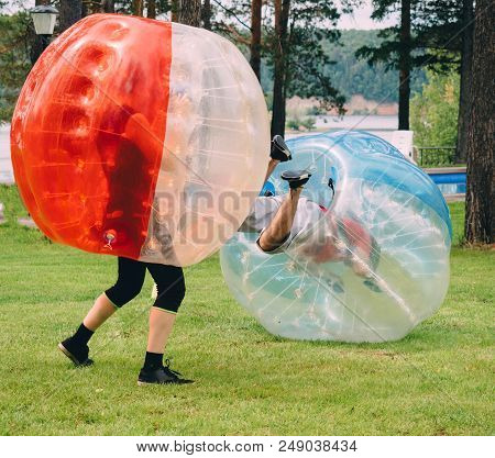 People Play Bumperball Zorbsoccer Outdoor. Summer Time