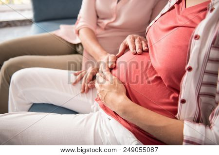 Hands Of Mother. Close Up Of Beautiful Hands Of Beaming Mother Touching Pregnant Tummy Of Her Niece