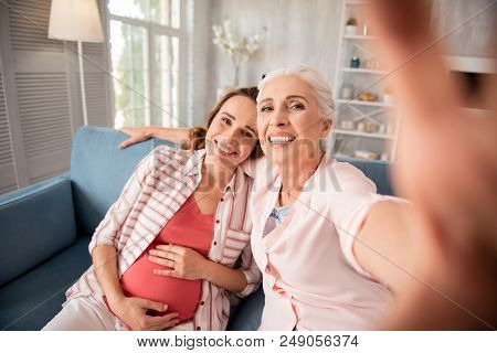 Making Photo. Dark-haired Beaming Woman Feeling Excited While Making Photo With Her Anticipating Dau
