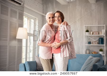 Caring Mother. Caring Smiling Mother Feeling Loved While Hugging Her Dear Pregnant Daughter Standing
