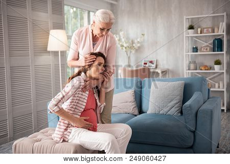 Experiencing Pain. Dark-haired Pregnant Woman Feeling Disturbed While Experiencing Strong Pain In He